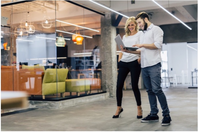 A man and a woman looking at a computer and laughing.